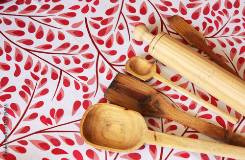 Fondo floral rojo con utensilios de cocina de madera en la esquina inferior derecha, cuchara de madera, rodillo de madera, pala de madera, fondo rojo photo