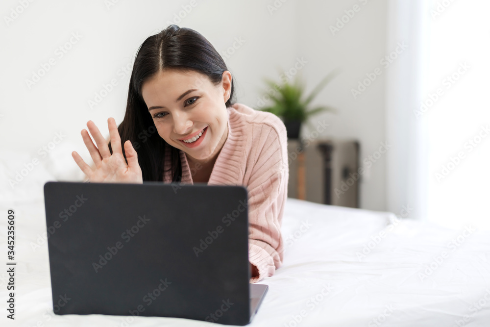 Smiling of young beautiful pretty woman relaxing and using technology laptop computer lying on bed and joyful on weekend in the bedroom.girl checking social apps and working.technology online concept Smiling of young beautiful pretty woman relaxing and using technology laptop computer lying on bed and joyful on weekend in the bedroom.girl checking social apps and working.technology online concept