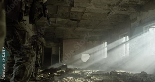 Group of soldiers moving fast through ruined building in search and rescue operation
