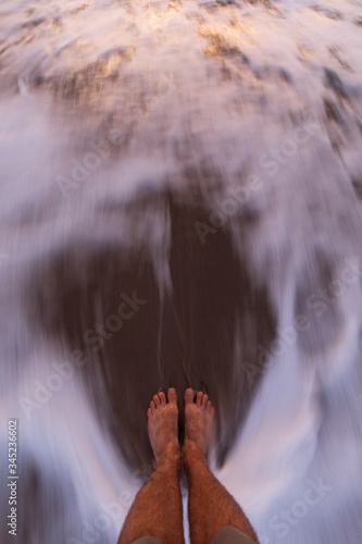 Feet in a moving waves at sunrise