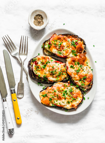 Roasted eggplant with ham, tomatoes and mozzarella - delicious appetizer, tapas on a light background, top view