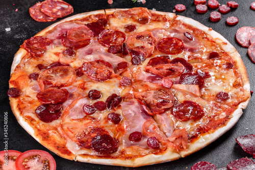 Pepperoni pizza with mozzarella cheese, salami, tomatoes, pepper and spices