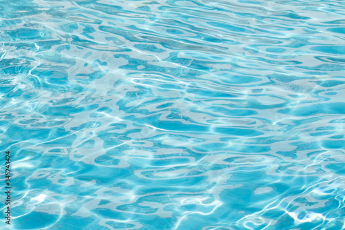Water surface background. Blue pool water with sun reflections. Ripples of water in the pool.