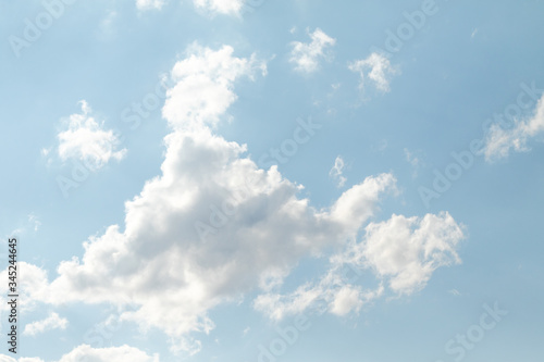 White relief clouds in the blue sky.The background of clouds floating across the sky is saturated with the texture of the material  which forms a recognizable relief of clouds with whimsical outlines.