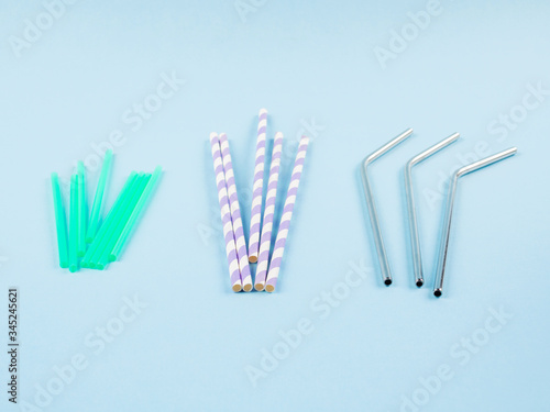 Different material drinking straws on pastel blue background - plastic  paper and eco friendly plastic free stainless steel reusable straws. Flat lay