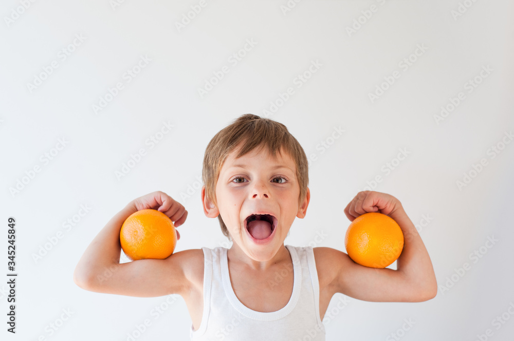 strong young little caucasian kid with oranges on muscles with open mouth strong young little caucasian kid with oranges on muscles with open mouth