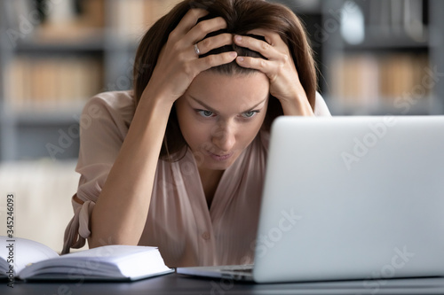 Stressed unhappy woman looking at laptop screen close up, touching head, feeling exhausted, tired young female student or freelancer working on computer, having headache or problem with work