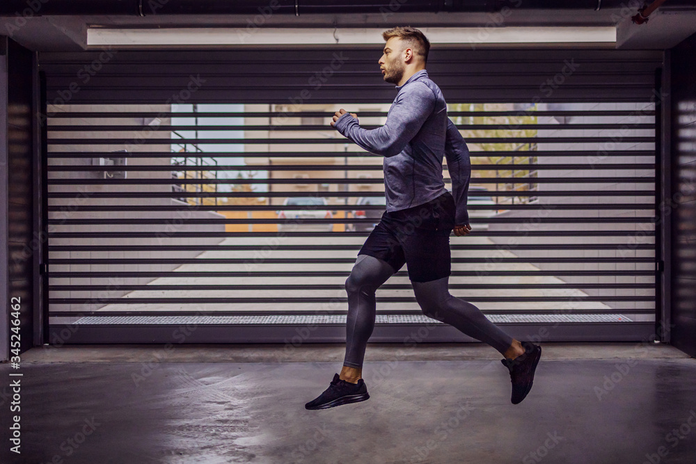 Fototapeta premium Young attractive muscular sportsman running in underground garage.