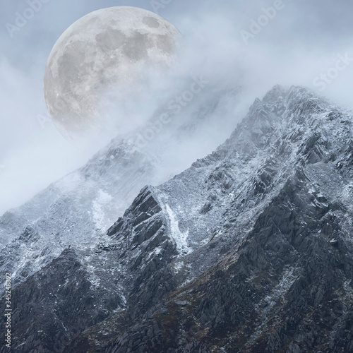 Epic digital composite image of Supermoon above mountain range giving very surreal fantasy look to the dramatic landscape image © veneratio