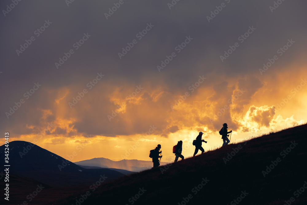 Group of hikers walks at majestic sunset in mountains Group of hikers walks at majestic sunset in mountains