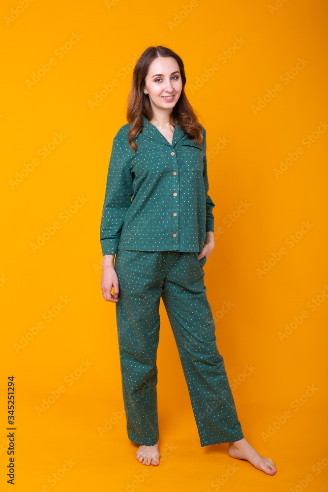 Smiling young girl in pajamas home wear posing while resting at home isolated on yellow background studio portrait. Relax good mood lifestyle concept. Smiling young girl in pajamas home wear posing while resting at home isolated on yellow background studio portrait. Relax good mood lifestyle concept.