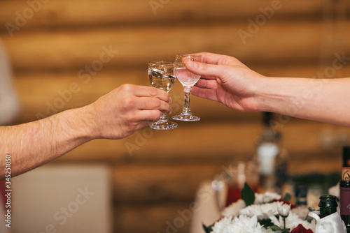 hands of a group of friends clinking glasses of vodka and celebrating the holiday