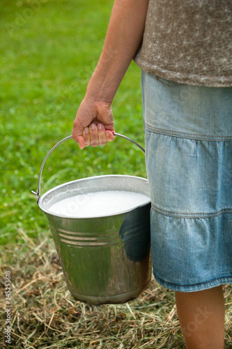 Milkmaid holding bucket with milk photo