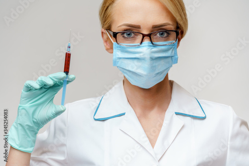 Doctor or woman nurse wearing protective mask holding syringe