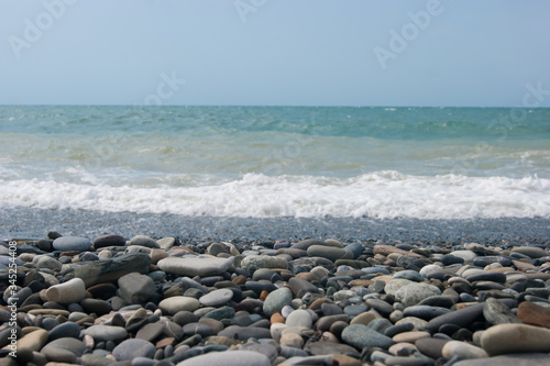 A small storm three or four points at sea, the wave hits the shore with a large pebble.