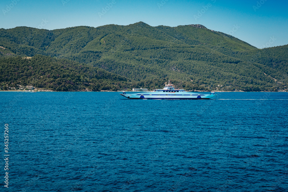 White yachts and catamarans in a bay near a tropical island. Sailing yacht and motor catamaran for charter and bareboat in the lagoon by the beach. Blue sea, white vessels during sport ocean cruise