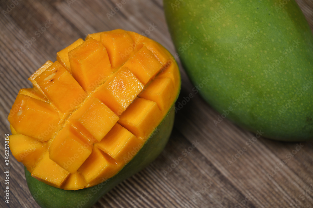Close up of famous sweet mango in North Malaysia called Harum Manis isolated on top of dark wooden background. Sweet and juicy. Malaysian and Asian favourite mango. Close up of famous sweet mango in North Malaysia called Harum Manis isolated on top of dark wooden background. Sweet and juicy. Malaysian and Asian favourite mango.