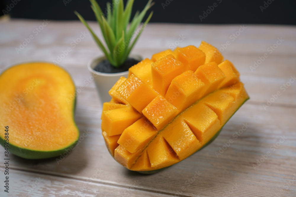 Close up of famous sweet mango in North Malaysia called Harum Manis isolated on top of wooden background. Sweet and juicy. Malaysian and Asian favourite mango. Close up of famous sweet mango in North Malaysia called Harum Manis isolated on top of wooden background. Sweet and juicy. Malaysian and Asian favourite mango.