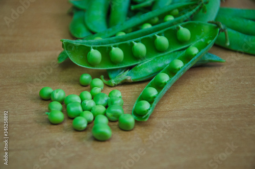 Pods of green peas with peas on a wooden background. Natural foods.