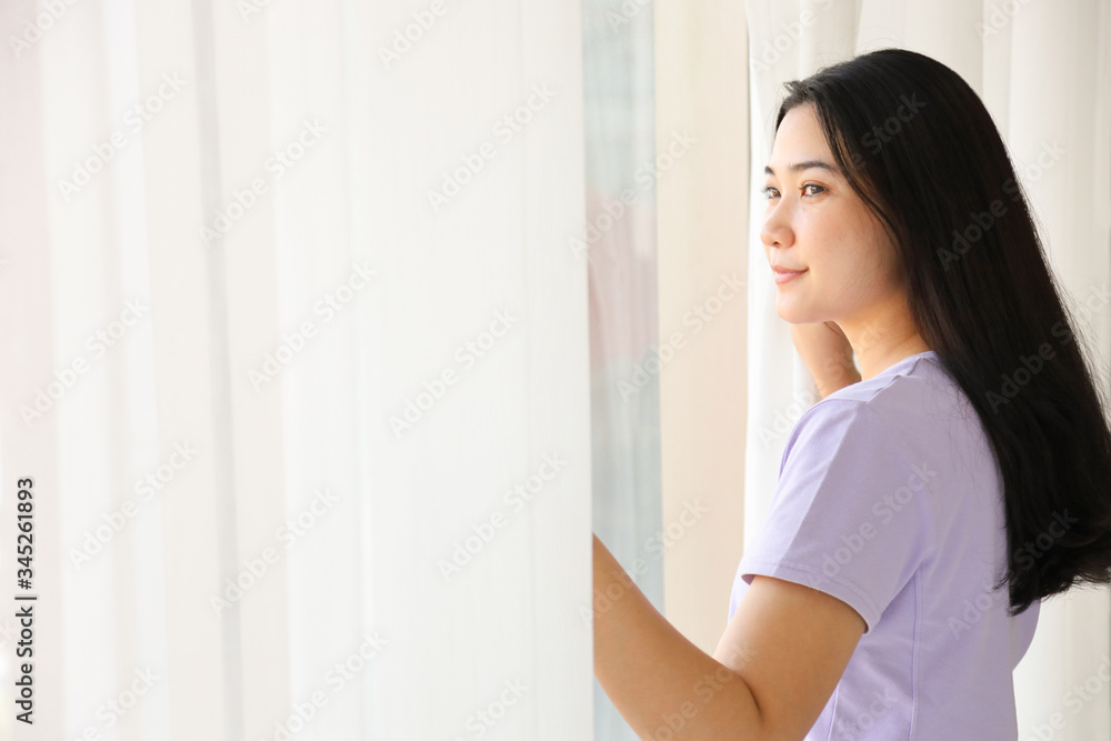 Asian female with long black hair open the curtain while smiling and looking out the glass window in the new day morning cozy vibe atmosphere with copy space Asian female with long black hair open the curtain while smiling and looking out the glass window in the new day morning cozy vibe atmosphere with copy space