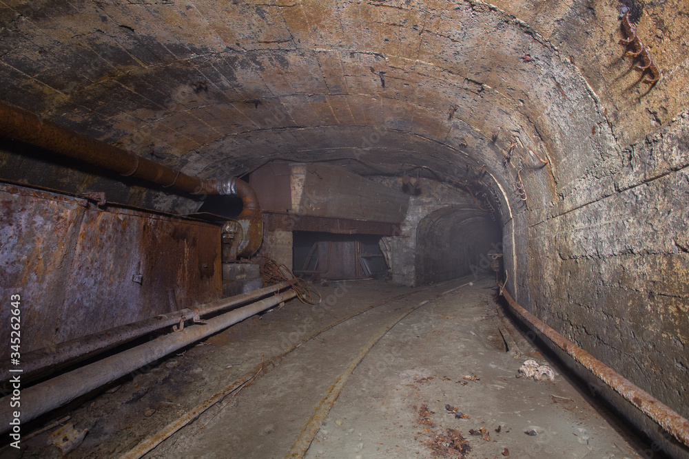 Underground abandoned iron ore mine tunnel with concrete timbering and rails Underground abandoned iron ore mine tunnel with concrete timbering and rails