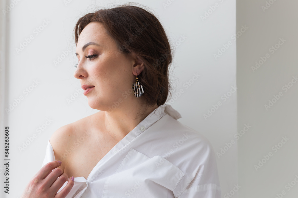 Close-up of fashion shoot of young brunette woman with elegant hairstyle in white studio. Trendy style concept.
