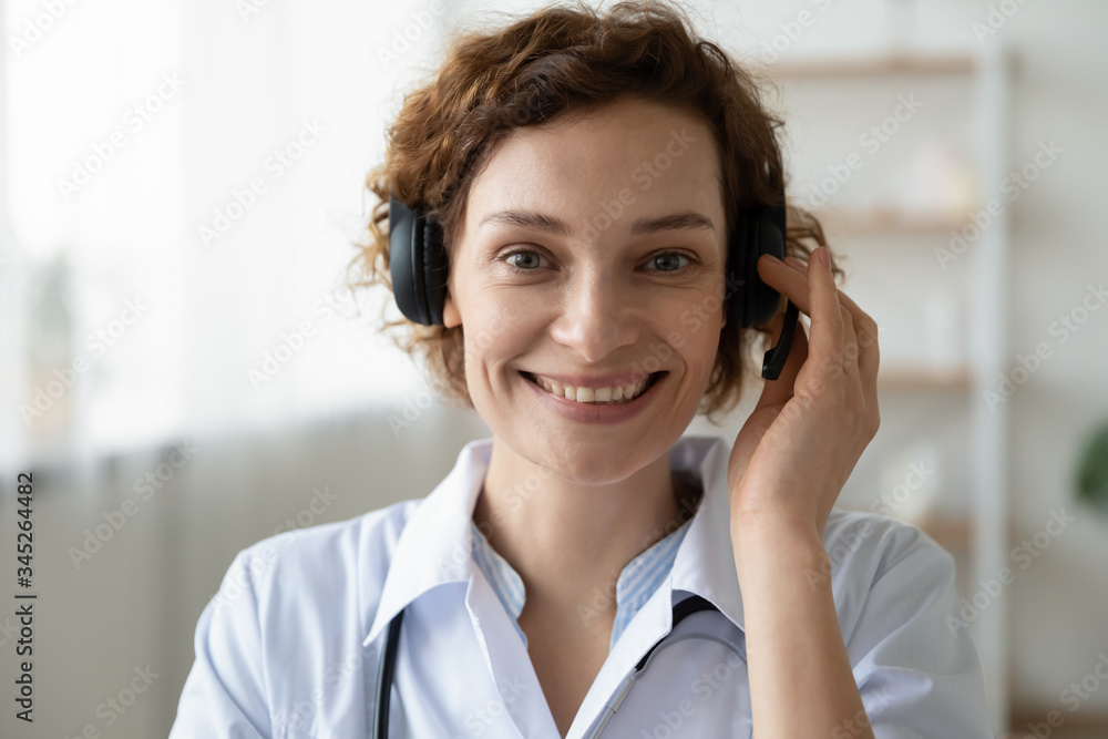 Smiling female doctor wearing headset looking at camera. Remote online medical chat consultation, telemedicine distance services, virtual physician conference call concept. Head shot close up portrait Smiling female doctor wearing headset looking at camera. Remote online medical chat consultation, telemedicine distance services, virtual physician conference call concept. Head shot close up portrait