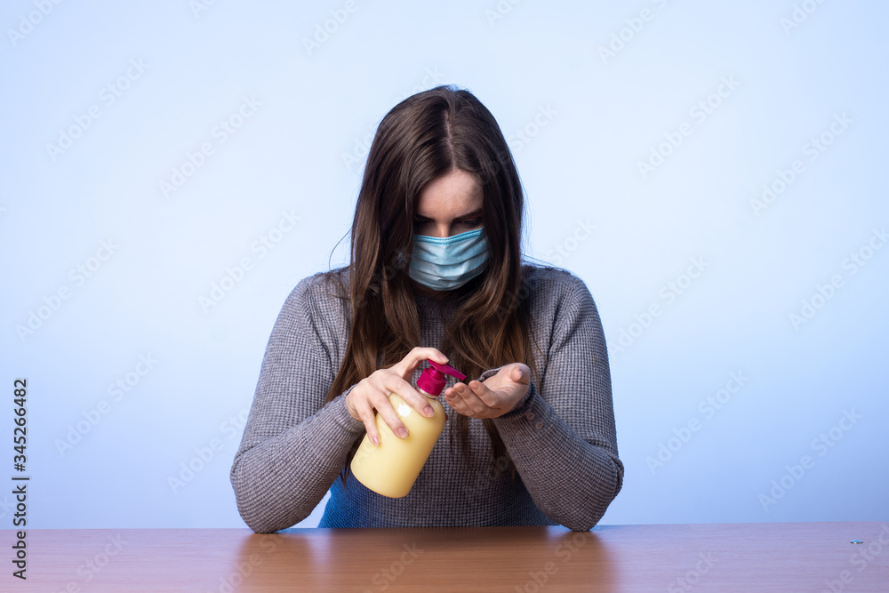 a young girl in a medical mask squeezes soap from a jar onto her hand ...