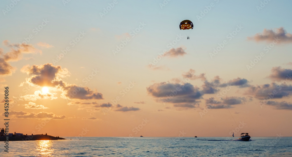 Motor boat is dragging of parachute on sunset sky Motor boat is dragging of parachute on sunset sky