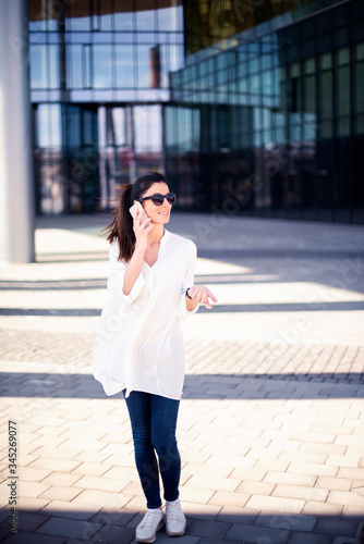 Free Download Businesswoman making a call while standing on the street in front of the office building - GFXLoad