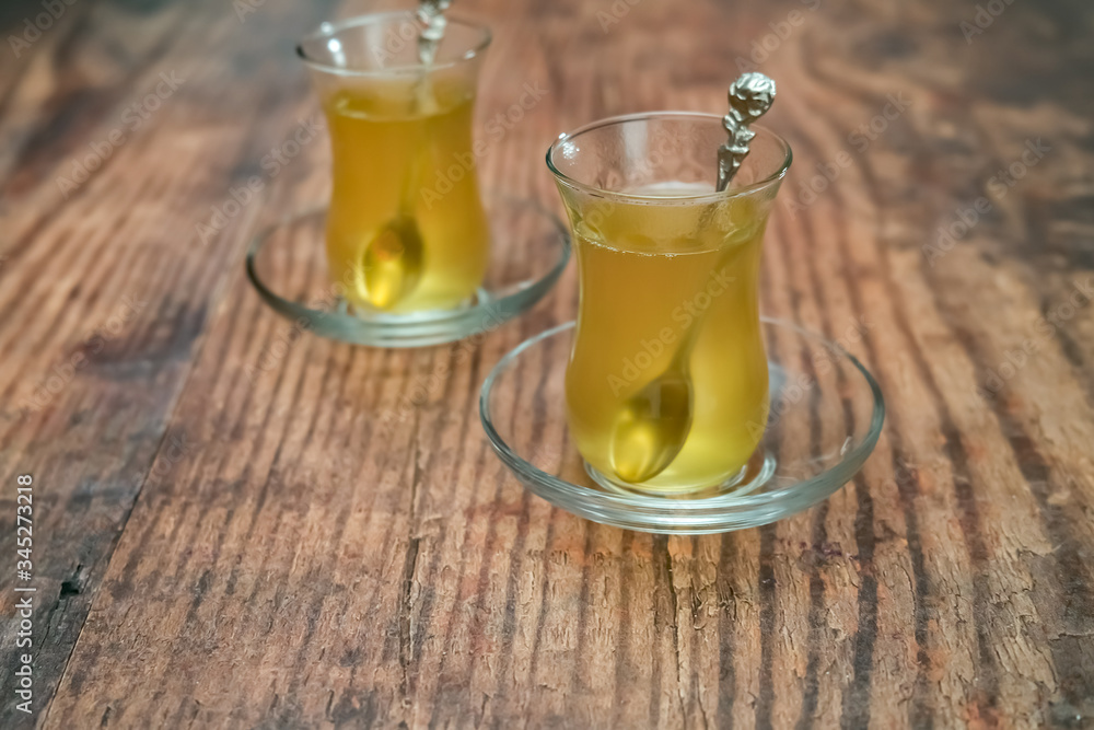 Turkish fruit tea served in traditional glass cups and saucers on a wooden table with intentional selective focus and shallow depth of field Turkish fruit tea served in traditional glass cups and saucers on a wooden table with intentional selective focus and shallow depth of field