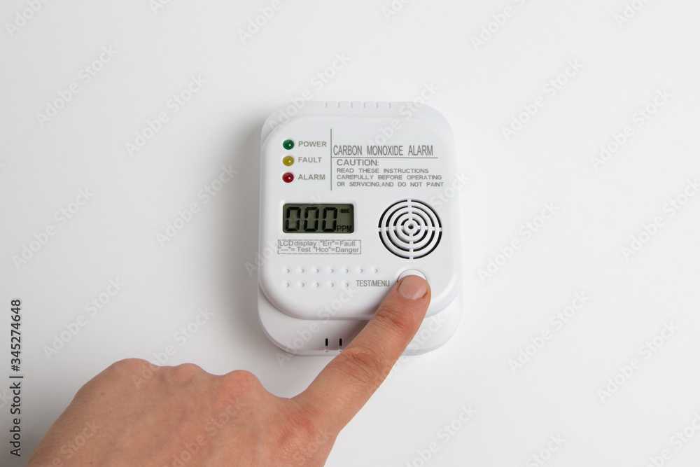 testing carbon monoxide detector on a white wall. Stay home safe. Home control and security.  CO detector - obrazy, fototapety, plakaty 