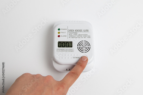 testing carbon monoxide detector on a white wall. Stay home safe. Home control and security.  CO detector photo