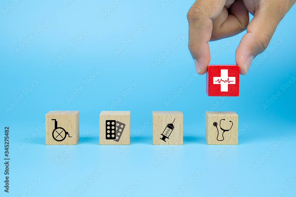 Hand picking up health icon on cube wooden toy blocks with other medical icons. Concepts of illness treatment and health safety insurance. Hand picking up health icon on cube wooden toy blocks with other medical icons. Concepts of illness treatment and health safety insurance.