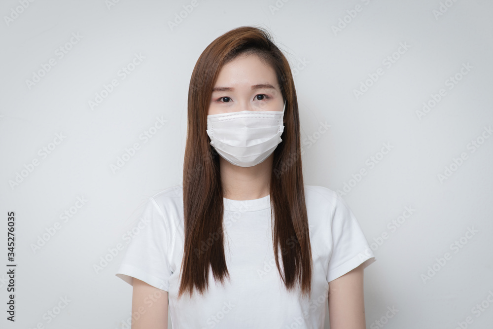 Asian Young woman in a white t-shirt and wear a medical mask that protects against the spread of coronavirus or COVID-19 disease. Studio Portrait with White Background. Asian Young woman in a white t-shirt and wear a medical mask that protects against the spread of coronavirus or COVID-19 disease. Studio Portrait with White Background.