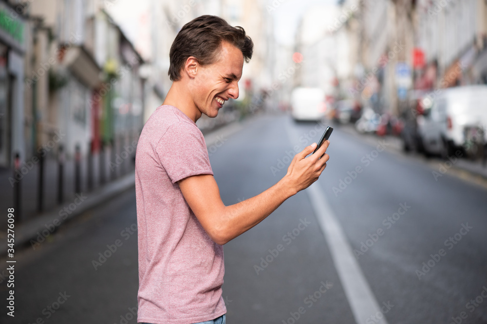 happy man walking across city street looking at mobile phone happy man walking across city street looking at mobile phone
