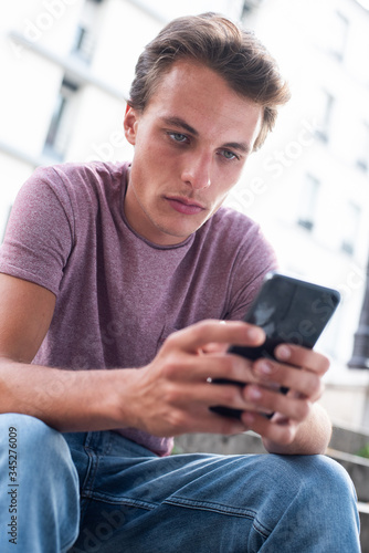 Close up handsome young man looking at mobile phone outside