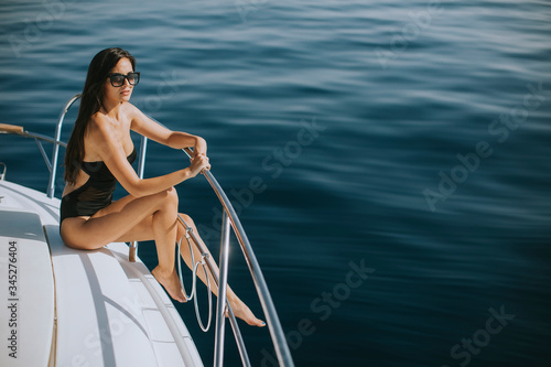 Young woman in swimwear and sunglasses sitting on a yacht deck