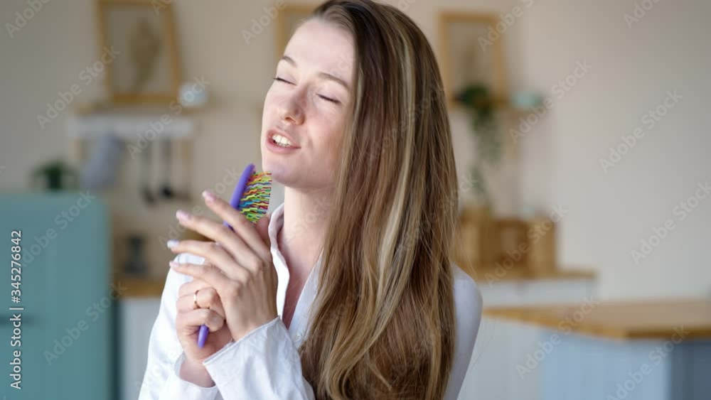 Attractive cheerful woman dancing on bed and singing with comb like microphone at home Attractive cheerful woman dancing on bed and singing with comb like microphone at home