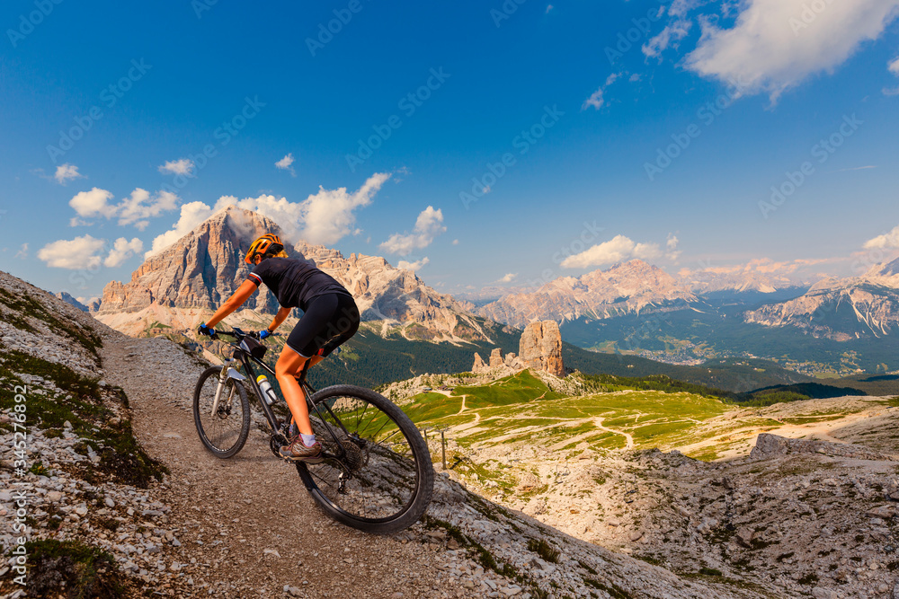 Fototapeta premium Cycling outdoor adventure in Dolomites. Cycling woman in Dolomites landscape. Woman cycling MTB enduro trail track. Outdoor sport activity.