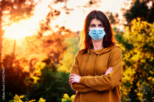 woman with face mask during coronavirus crisis in a natural environment - social distancing concept