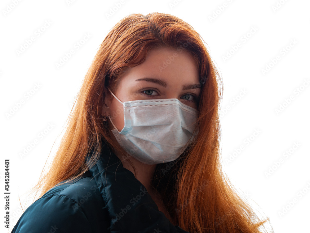 Horizontal shot of ill redhead girl wears medical mask to protect from catching disease, in black jacket, stands outdoor, suffers from epidemic illness, isolated background Horizontal shot of ill redhead girl wears medical mask to protect from catching disease, in black jacket, stands outdoor, suffers from epidemic illness, isolated background