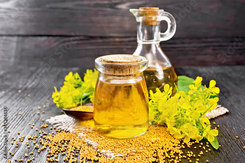 Oil mustard in jar and decanter with flower on wooden board