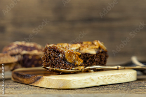 Close up toffee cake on steel spoon and on wooden background.