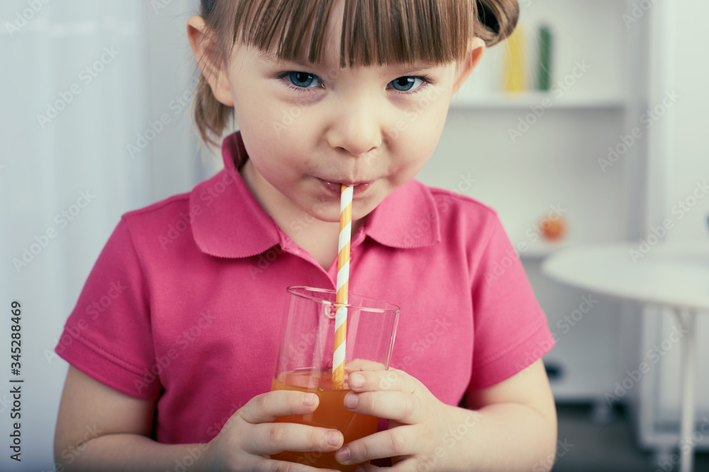 Cute little girl drinks orange juice at home. Cute little girl drinks orange juice at home.