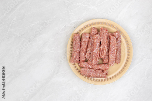 Top view of raw minced meat kebabs on the plate