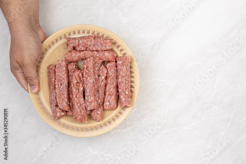 Top view of raw minced meat kebabs on the plate