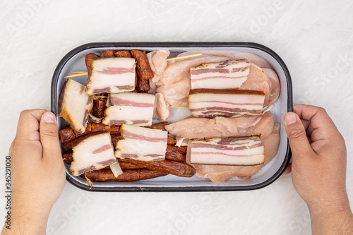 Top view of mixed meat prepared for grill. Bacon kebabs sausages and chicken breasts.