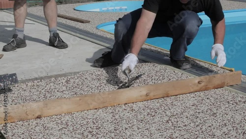 Laying the floor around the outdoor pool. The worker places a stone carpet with resin.
(Shallow DOF).