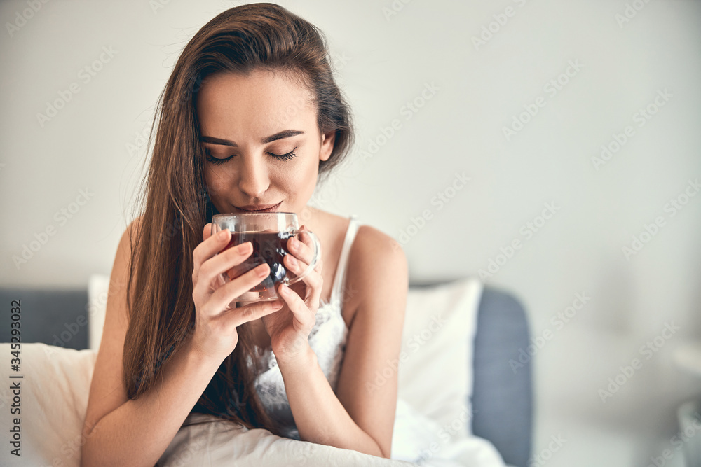 Caucasian happy woman drinking tea in bedroom Caucasian happy woman drinking tea in bedroom